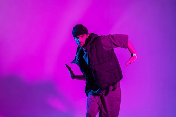 stock image Fashionable professional dancer man in trendy clothes dancing in color studio with pink and neon lights