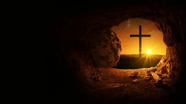 Easter and Good Friday concept, empty tomb with cross on mountain with amazing sunrise. Creative idea Easter. Religion and Christianity. Open empty cave with sunset view. Free copy space for design