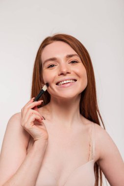 Makyajlı sevimli bir gülüşü olan güzel, güzel, kızıl saçlı bir kadın model. Güzellik ve cilt bakımı