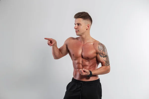 Przystojny Muskularny Mężczyzna Umięśnionym Ciałem Fryzurą Pokazującą Bicepsy Wskazującą Palcem — Zdjęcie stockowe