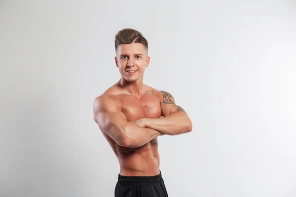 Muscular young healthy fit guy with a hairstyle with a muscular body stands hand in hand on a white background in the studio
