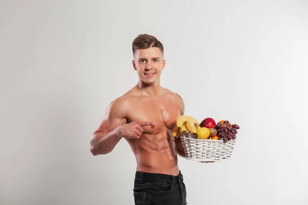 肌肉发达的男人拿着一个水果篮 手指放在白色的背景上 运动和健康的生食水果 — 图库照片