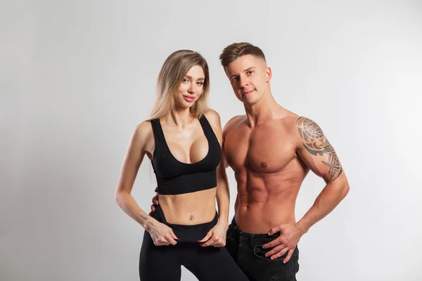 Beautiful athletic young fitness couple on a white background. Pretty slim fit woman and handsome muscular athletic man with naked torso in studio. Slimming and diet concept