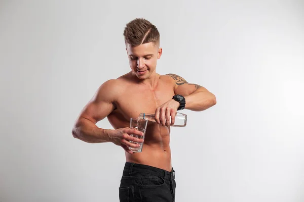 英俊而快乐的运动健将 肌肉发达的男子将水倒入白色背景的杯子中 — 图库照片