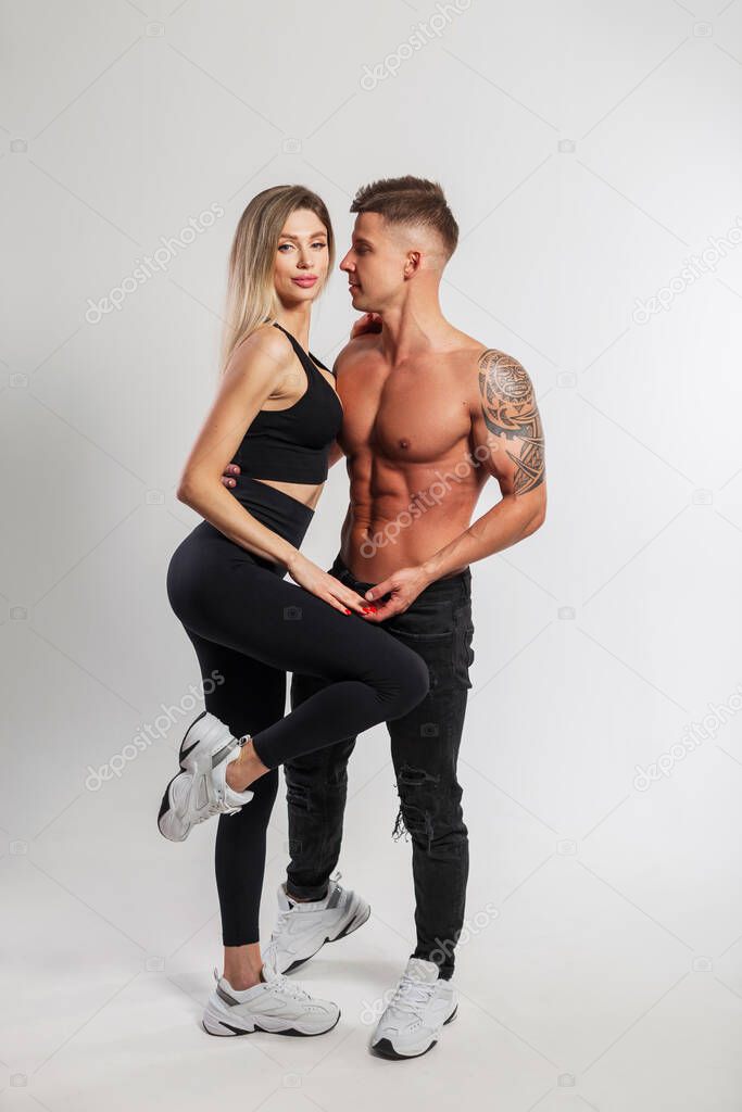 Hermosa pareja de fitness con ropa deportiva con estilo está posando en una  calle de la ciudad
