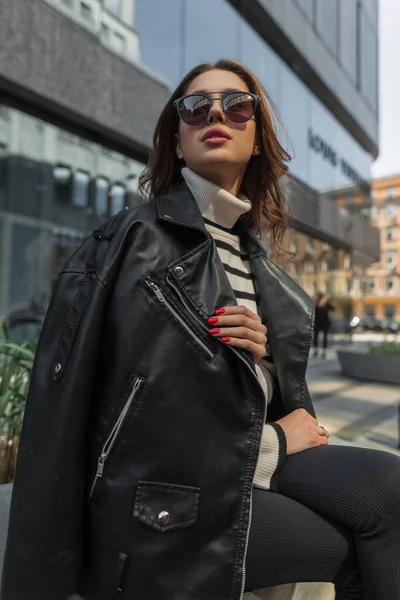 时尚女模 身穿黑色岩石皮夹克 头戴时髦太阳镜 坐落于现代购物中心附近的城市 — 图库照片