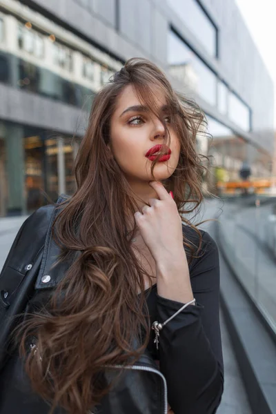 都会で乱雑な髪で革のジャケットの散歩とファッショナブルな黒のカジュアルな服で赤い唇を持つエレガントな若いファッション女性 — ストック写真