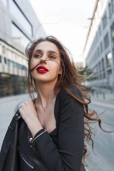 美しいエレガントなシックな女の子で赤い唇でファッション黒の服に革のジャケットは晴れた日に街を歩く — ストック写真