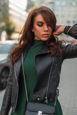 Moda kıyafetleri içinde, deri ceketli, şık, şık bir çanta taşıyan, şık, yeşil elbiseli, şık bir kadın mankeni.