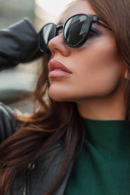 Kapalı moda moda kadın portresi. Güzel, şık, havalı bir kadın portresi. Temiz bir yüz teni ve modaya uygun giyinmiş seksi dudakları olan, şehirde siyah güneş gözlüklü.