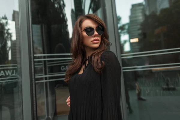 雅致漂亮的年轻漂亮的女模特 一头乌黑的头发 戴着凉爽的老式太阳镜 穿着黑色时髦的都市服装 — 图库照片