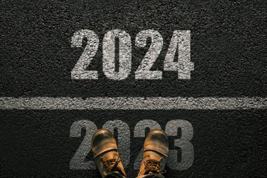İnsan asfalt üzerinde yürür ve 2024 'e kadar çizgiyi geçer. Yeni yıl 2024. Erkeklerin deri ayakkabılı bacakları 2024 'e kadar gidiyor. 2023 'ün sonu ve 2024' ün başı