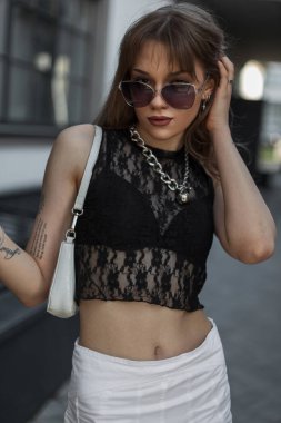 Havalı güneş gözlüklü, şık yazlık elbiseli, şık dantelli etekli, şehirde çanta taşıyan güzel moda seksi bayan.