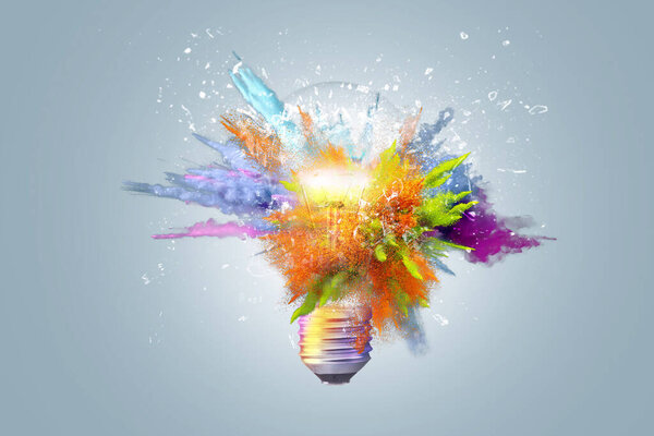 Creative concept light bulb explodes with colorful water colors on a light blue background. Think different, creative idea. Productivity and creativity