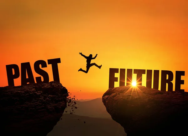 Successful man jumps over a cliff with the text Future at sunset, concept. Leap from past to future, creative idea. Rock at sunrise