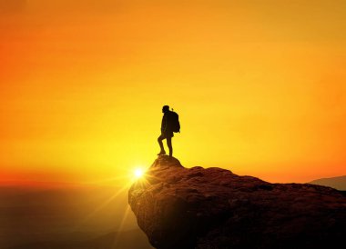 Günbatımında başarılı bir adam, konsept. Takım liderliği dağda duruyor, yaratıcı bir fikir. Uçuruma tırmanıyor ve seyahat ediyor..   