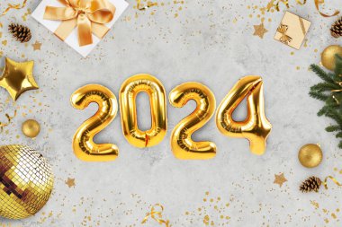 Yeni yıl altın topları 2024 lüks gri beton bir masa üzerinde hediyeler, altın disko topu, Noel ağacı dalları ve konfeti, üst manzara. Yeni yıl 2024 kartı, yaratıcı fikir.