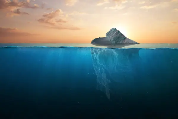 Ocean warming, concept. Iceberg in clear blue water and hidden danger under water at sunset. Iceberg - Hidden Danger And Global Warming Concept. Floating ice in ocean. Copy space for text and design.