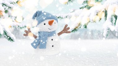 Atkısı ve şapkası olan güzel, eğlenceli bir kardan adam. Işıklı bir Noel ağacının yanında duruyor. Noel ve Yeni Yıl 2024 kartpostalları, yaratıcı fikir. Kış tebrik kartı, konsept.