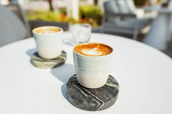 Delicious coffee in a vintage cup stands on a white table in a summer cafe on a sunny day