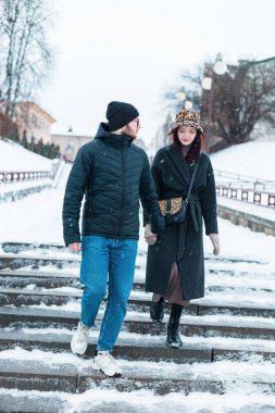 Moda kıyafetleri içinde genç bir çift şehirde kar yağarken merdivenlerden aşağı iniyor. Güzel bayan ve yakışıklı adam birlikte yürür.
