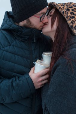 Güzel, genç aşıklar kahve içip dışarıda öpüşüyorlar. Yakışıklı bir adam bir kızı öper.