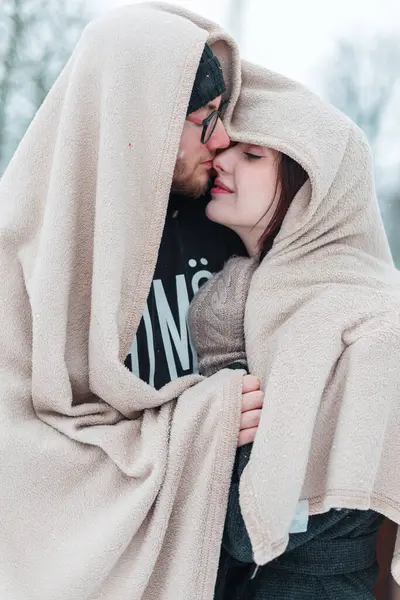 Kışın karlı parkta bej battaniyeli güzel, mutlu aşıklar. Sevgi ve kucak