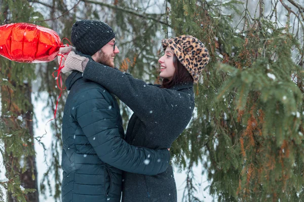 Güzel, genç aşıklar, şık kıyafetler içinde. Kışlık bir parkta, Noel ağaçlarında sarılıp eğleniyorlar.