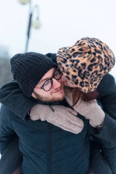 Havalı kışlık giysiler içinde, kar yağarken dışarıda eğlenen mutlu, güzel, pozitif, genç aşıklar.
