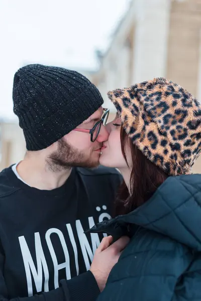 Şık kışlık giysiler içinde şehirde öpüşen genç ve güzel aşıklar.