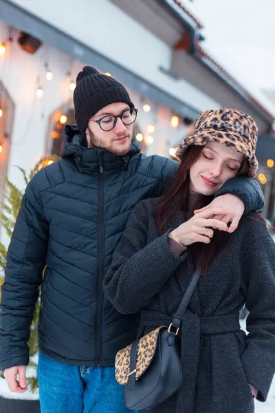 Güzel, şirin, modaya uygun, şık giyinmiş aşıklar Noel dekoru binasının yakınındaki sokakta birlikte yürüyorlar.