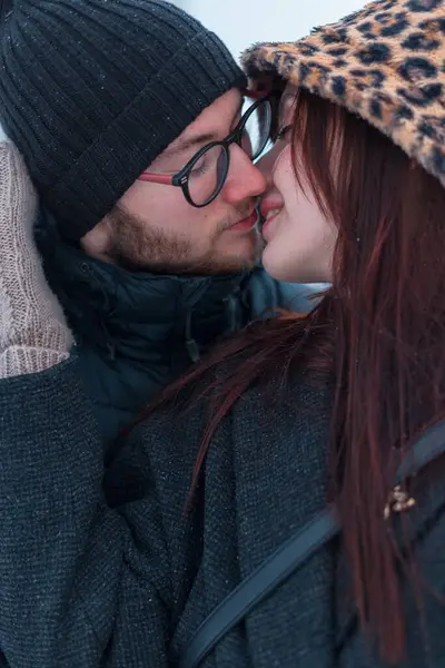 Moda, genç, güzel aşıklar, şık kış kıyafetleri içinde açık havada öpüşüyorlar.