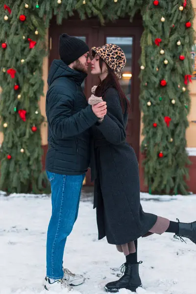 Moda kıyafetleri içinde genç ve güzel aşıklar şehrin kapısında Noel süsüyle bekliyorlar.