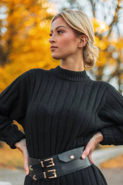 Güz parkında sarı yapraklı, siyah, uzun süveterli şık sarışın bir kadın. Güzel bir kız.