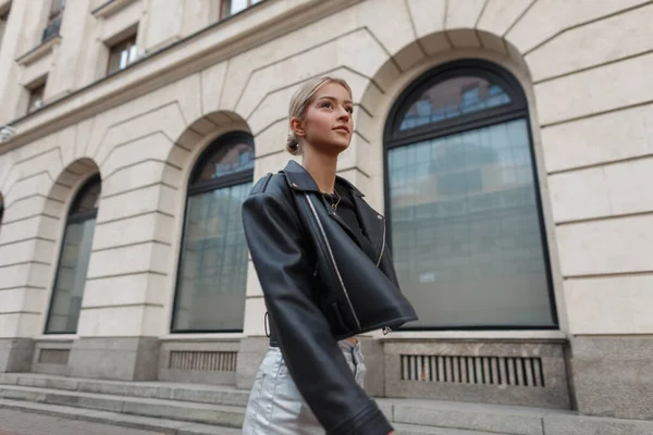 Şehirde eski bir ceketin yanında deri ceketli güzel bir manken geziyor.