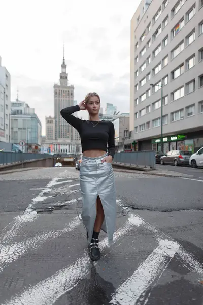 Moda elbisesi içinde, siyah bluzlu ve gümüş etekli güzel, genç ve şık bir kız şehirde yol boyunca yürüyor..