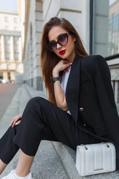 街のステップにスタイリッシュなバッグが付いている流行の黒い服のヴィンテージのサングラスが付いている美しいファッションビジネス女性モデル かわいい都市の女性 — ストック写真