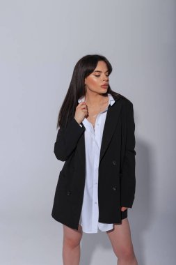 Moda modası güzel, taze, çekici iş kızı şık, büyük beden bir spor ceket ve beyaz gömlekle stüdyoda beyaz bir arka planda duruyor.