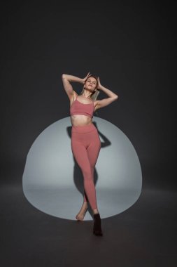 Sıska, güzel, spor kıyafetli yoga kadını. Stüdyoda siyah arka planda üst ve taytlı poz veriyor.