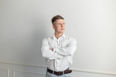 Beyaz arka planda beyaz gömlekli, yakışıklı, başarılı bir menajer.