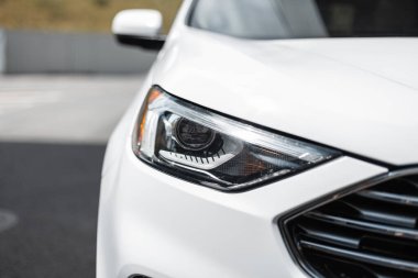 Şehirde optik farlı, modern güzel SUV beyaz araba, yakın plan.