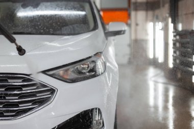 Farlı beyaz SUV arabası oto yıkamada yıkandı.