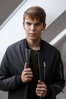Kapalı mekanda siyah ceketli, saç stili olan yakışıklı bir genç.