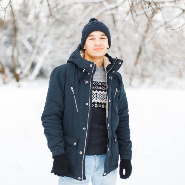 Şık şapkalı, kışlık ceketli ve kar parkında eski model süveterli şık erkek modeli.