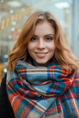 Güzel, mutlu, modaya uygun bir atkıyla gülümseyen bir kızın sokak kadını tatil portresi şehirde yürüyor.