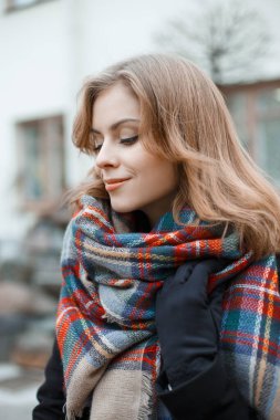 Güzel bir genç kız mankeni, modaya uygun renkli ekose atkısı ve sokakta eldiveni var. Güzel, şık bir bayan.