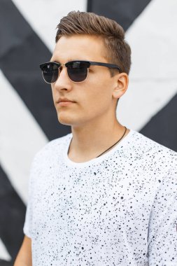 Sokakta klasik güneş gözlüklü, saç stili olan genç ve yakışıklı bir hippi.