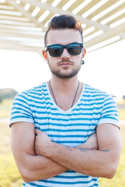 Eski moda saç stili ve güneş gözlüklü moda tişörtlü yakışıklı bir adam.