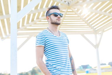 Güneşli bir günde plajda çizgili tişörtlü, moda gözlüklü şık hippi.