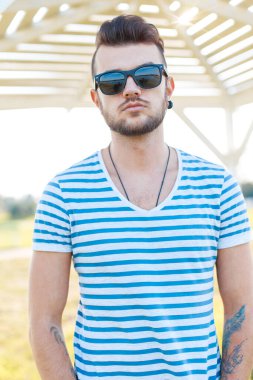 Moda gözlüklü havalı hippi plajda şık çizgili tişörtlü adam.